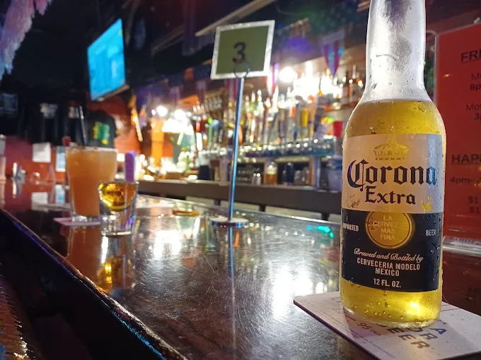 Slingshots bar interior — cold beer on the counter, colorful tap handles and bottles lining the bar